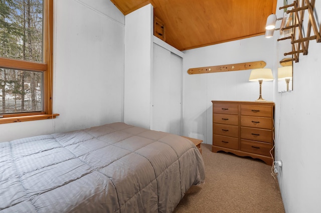 bedroom with lofted ceiling, a closet, carpet, and wood ceiling