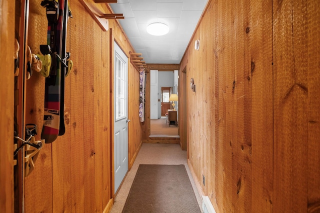 corridor with light colored carpet and wooden walls