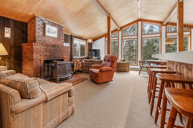 living room with vaulted ceiling with beams, wood ceiling, a wood stove, carpet flooring, and wooden walls