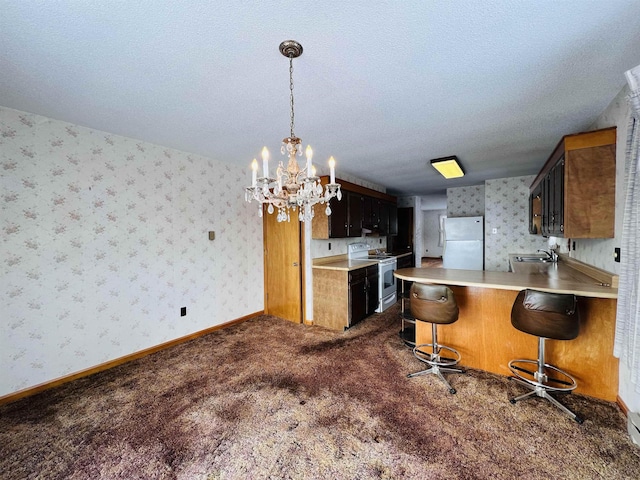 kitchen featuring dark colored carpet, white appliances, a peninsula, baseboards, and wallpapered walls