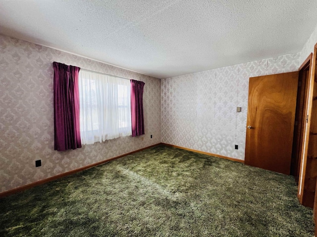 empty room with carpet floors, wallpapered walls, baseboards, and a textured ceiling