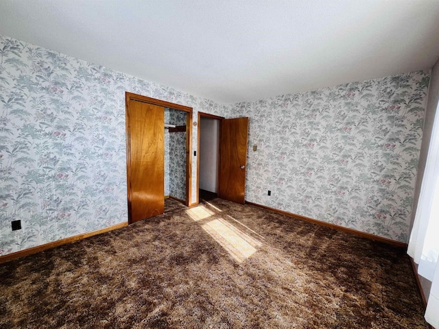 unfurnished bedroom with carpet floors, wallpapered walls, and baseboards