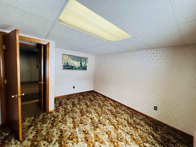 unfurnished bedroom with carpet, a paneled ceiling, baseboards, and wallpapered walls