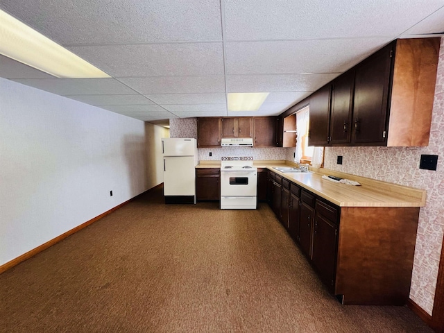 kitchen featuring white appliances, light countertops, under cabinet range hood, and baseboards