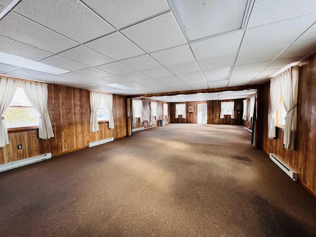 interior space with a baseboard heating unit and wooden walls