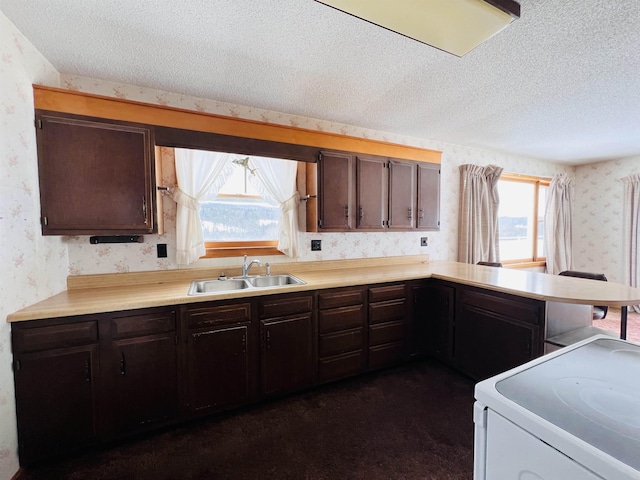 kitchen with a textured ceiling, a sink, light countertops, white range with electric cooktop, and wallpapered walls