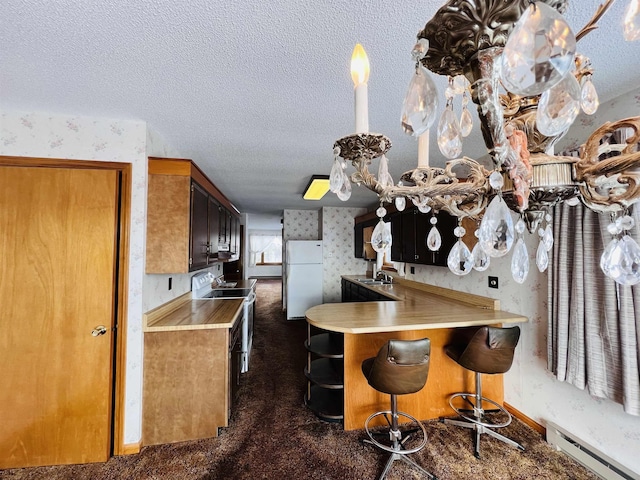 kitchen featuring electric stove, a baseboard radiator, freestanding refrigerator, a textured ceiling, and wallpapered walls