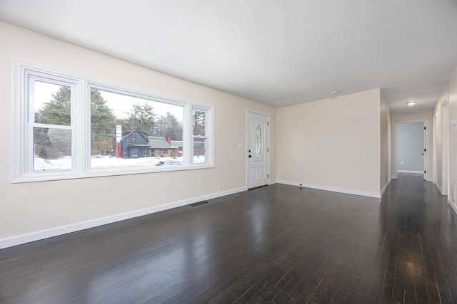 unfurnished room with baseboards, visible vents, and dark wood-style flooring