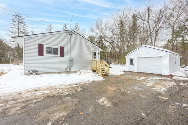 view of property exterior featuring an outbuilding, dirt driveway, and a detached garage