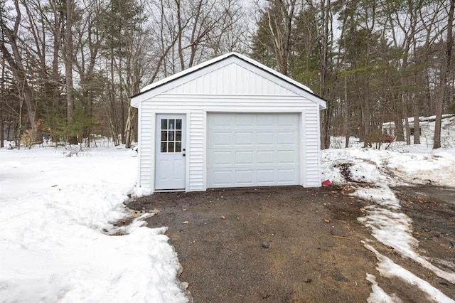 snow covered garage featuring a detached garage and driveway