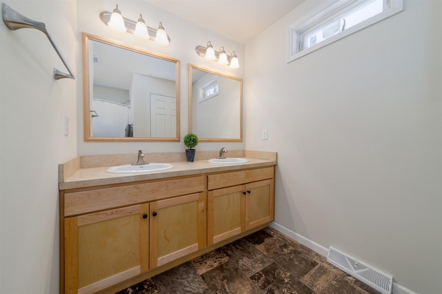 bathroom featuring visible vents, a sink, baseboards, and double vanity