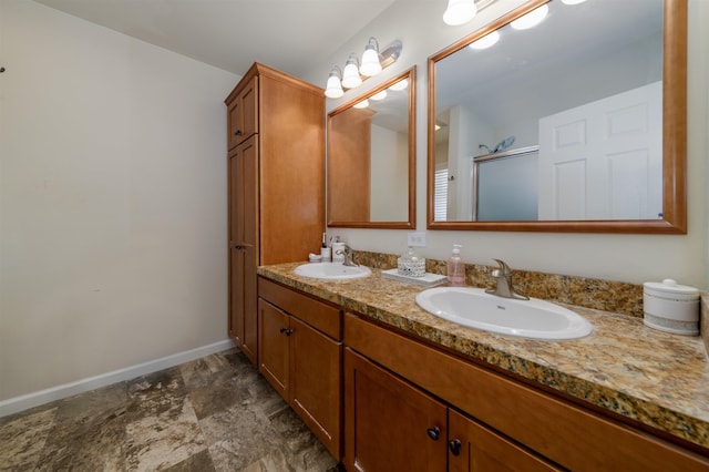 full bath with double vanity, a shower stall, baseboards, and a sink