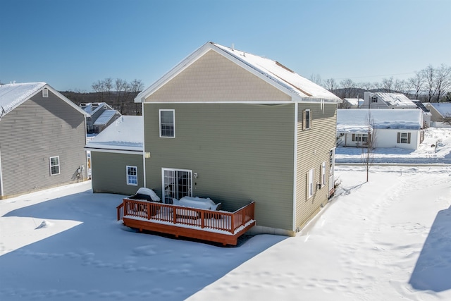 snow covered rear of property with a deck