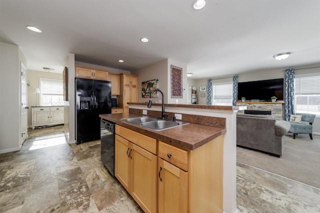 kitchen featuring a wealth of natural light, dark countertops, a sink, and black appliances