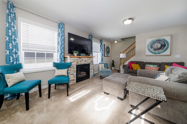 living room featuring a stone fireplace, stairway, carpet flooring, and baseboards