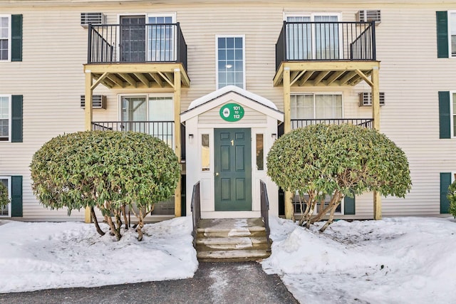 snow covered property entrance with a balcony