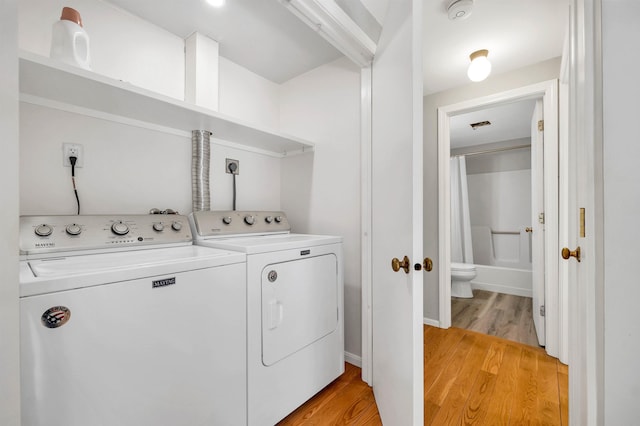 clothes washing area featuring laundry area, visible vents, light wood-style flooring, and washing machine and clothes dryer