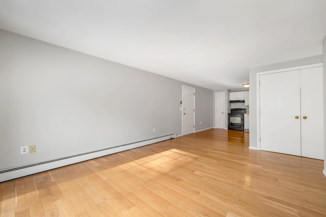 unfurnished living room featuring a baseboard heating unit and light wood-style floors