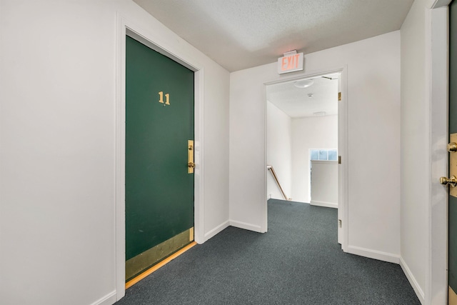 unfurnished room with baseboards, dark colored carpet, and a textured ceiling