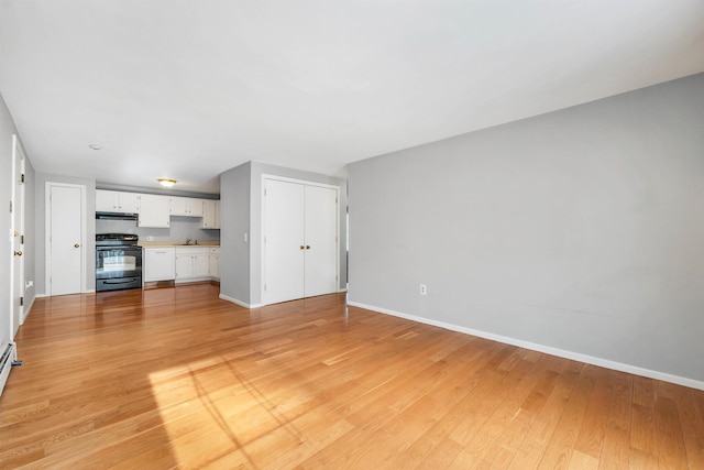 unfurnished living room featuring light wood finished floors, baseboards, and a sink