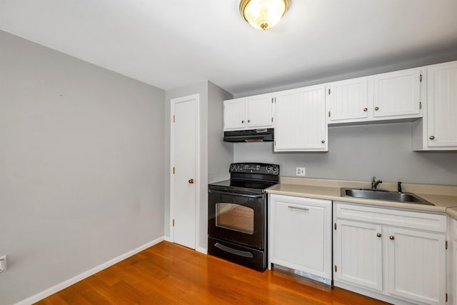 kitchen with black / electric stove, under cabinet range hood, wood finished floors, a sink, and baseboards