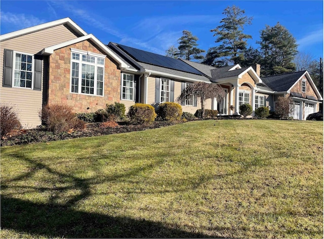 ranch-style house with a garage, stone siding, a chimney, roof mounted solar panels, and a front lawn