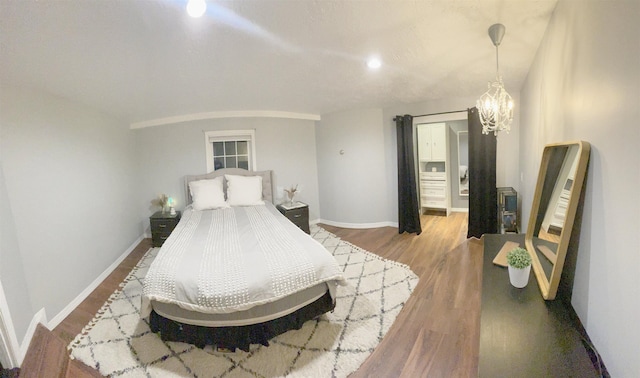 bedroom featuring a notable chandelier, baseboards, and wood finished floors