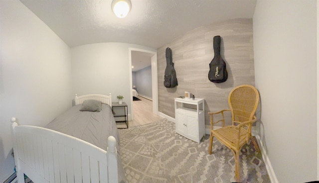 bedroom with vaulted ceiling, wood finished floors, and baseboards