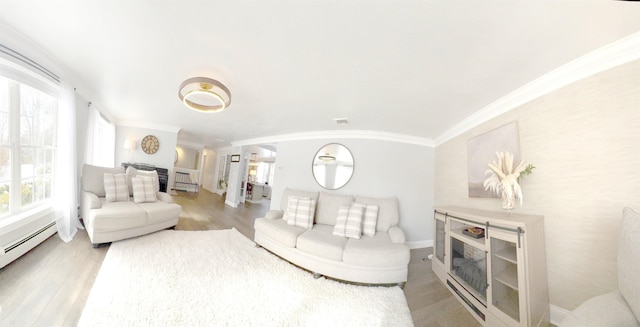 living room with ornamental molding, baseboard heating, light wood-style flooring, and baseboards