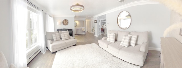 living room with a baseboard heating unit, visible vents, crown molding, and wood finished floors