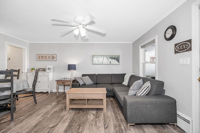 living area with a baseboard heating unit, ceiling fan, ornamental molding, and wood finished floors