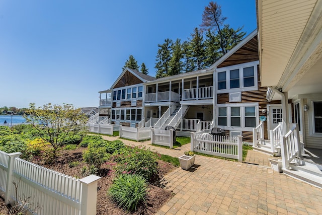 rear view of property with a water view, a patio area, and fence