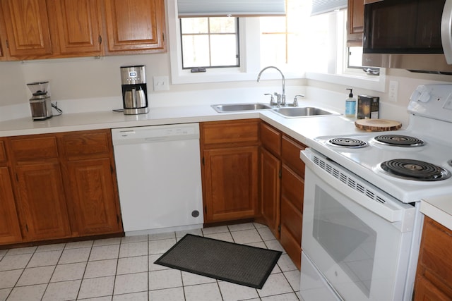 kitchen with light countertops, white appliances, brown cabinetry, and a sink