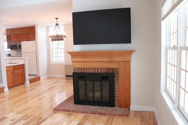 room details featuring wood finished floors, a sink, a brick fireplace, freestanding refrigerator, and stainless steel microwave