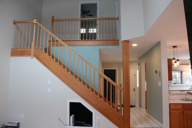 stairway featuring ceiling fan, recessed lighting, a towering ceiling, baseboards, and tile patterned floors