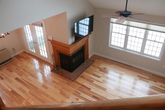 unfurnished living room featuring a brick fireplace, baseboards, and wood finished floors