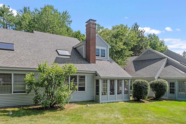 rear view of property featuring roof with shingles, a lawn, and a chimney