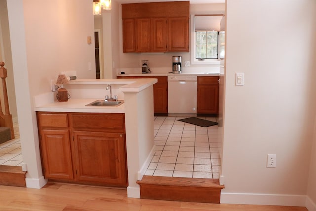 kitchen featuring light tile patterned floors, brown cabinetry, dishwasher, light countertops, and a sink