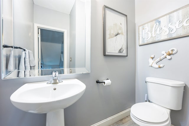 bathroom featuring wood finished floors, a sink, toilet, and baseboards