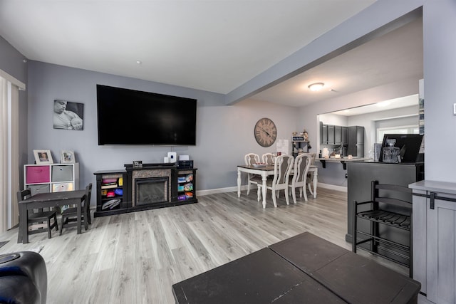 living area with light wood finished floors, a fireplace, and baseboards