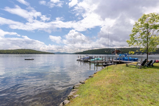 view of dock with a yard and a water view