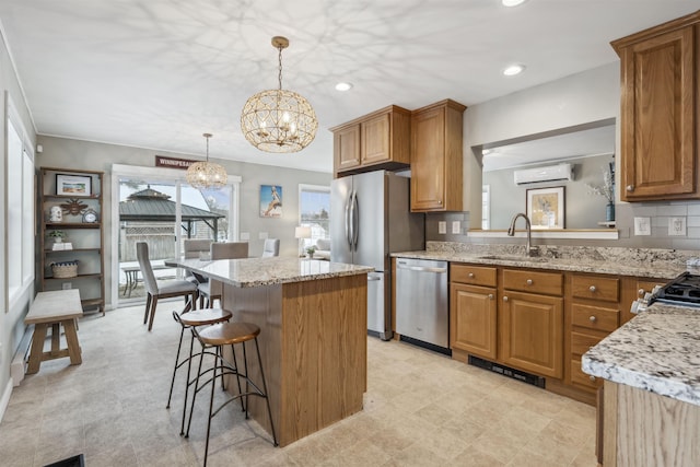 kitchen featuring appliances with stainless steel finishes, brown cabinetry, a sink, and a wall mounted air conditioner