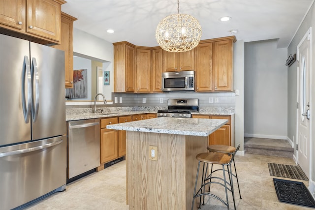 kitchen with tasteful backsplash, light stone counters, a center island, stainless steel appliances, and a sink