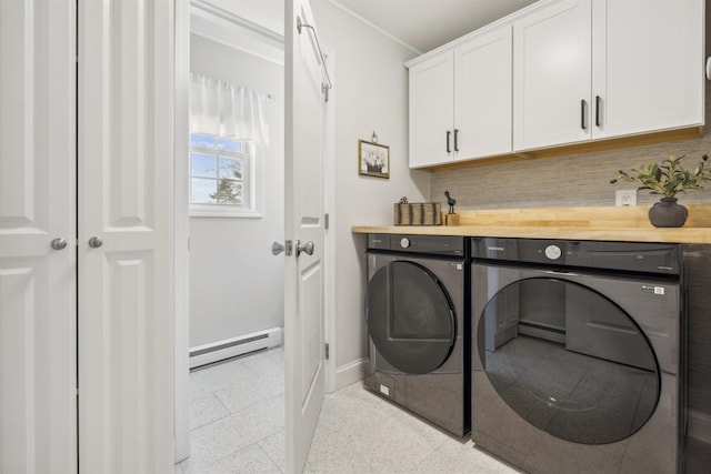 laundry room featuring a baseboard radiator, baseboards, cabinet space, washer and clothes dryer, and crown molding