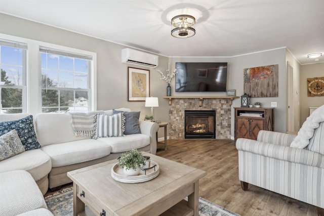 living area with a stone fireplace, ornamental molding, wood finished floors, and a wall mounted AC