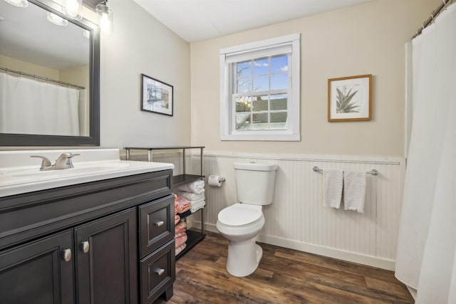 full bathroom with toilet, a wainscoted wall, wood finished floors, and vanity