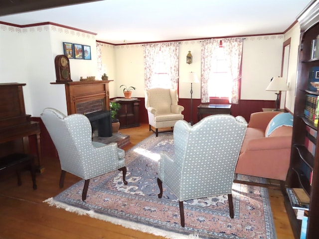 living area with a fireplace, wood finished floors, and crown molding