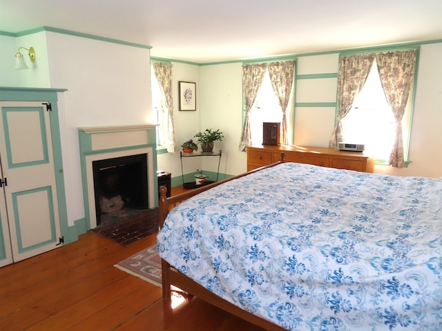 bedroom with a fireplace with flush hearth and wood-type flooring