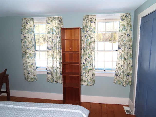 bedroom featuring wood finished floors, visible vents, and baseboards