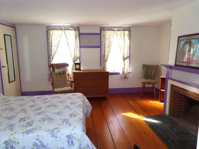 bedroom featuring baseboards, a fireplace, and hardwood / wood-style floors